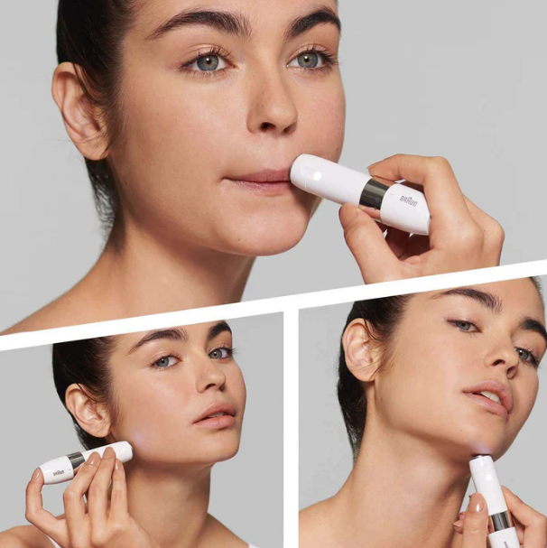 Woman using a skincare device on her face with a gray background